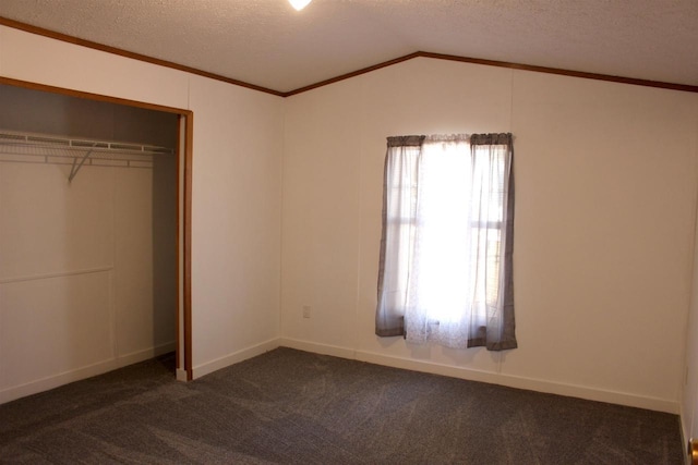 unfurnished bedroom with a textured ceiling, dark carpet, a closet, and vaulted ceiling