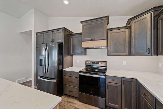 kitchen featuring vaulted ceiling, stainless steel appliances, light hardwood / wood-style floors, custom range hood, and dark brown cabinetry