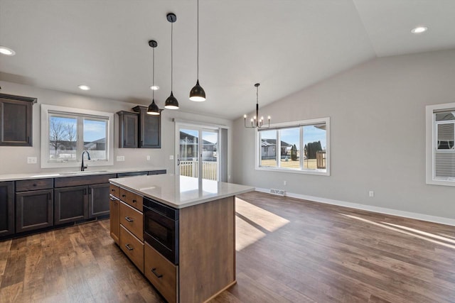 kitchen featuring sink, decorative light fixtures, a center island, vaulted ceiling, and dark brown cabinets