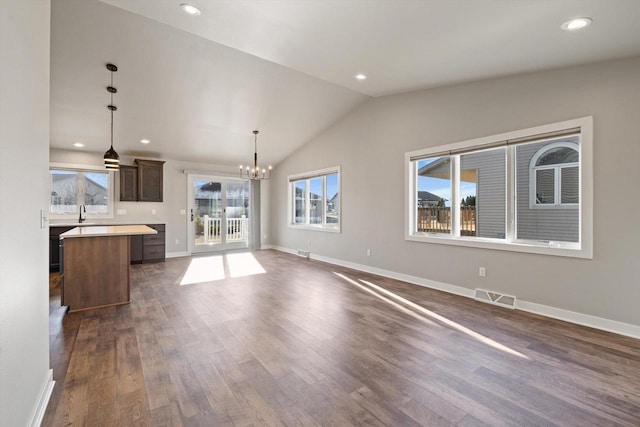 unfurnished living room featuring lofted ceiling, dark wood-type flooring, and a notable chandelier