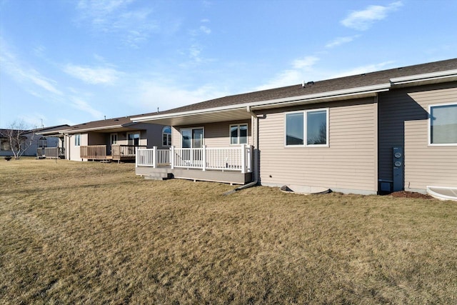 back of property with a wooden deck and a lawn