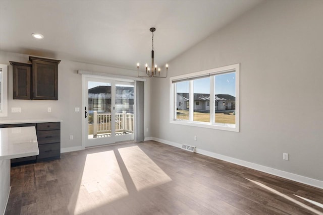 unfurnished dining area with lofted ceiling, dark hardwood / wood-style flooring, and a chandelier