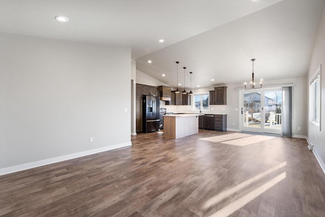 unfurnished living room with sink, dark wood-type flooring, high vaulted ceiling, and a chandelier