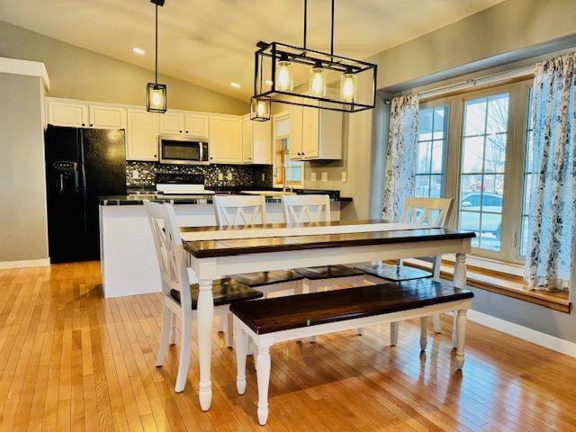 dining room with lofted ceiling and light hardwood / wood-style floors