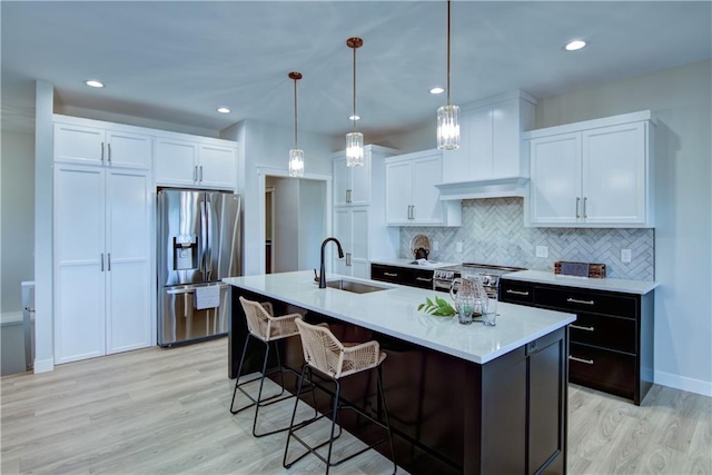 kitchen with an island with sink, appliances with stainless steel finishes, white cabinetry, and sink