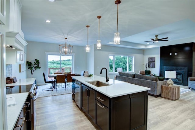 kitchen with sink, stainless steel appliances, a fireplace, dark brown cabinets, and a kitchen island with sink