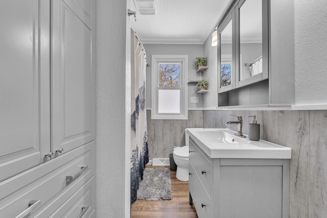 bathroom featuring toilet, ornamental molding, wood-type flooring, and vanity