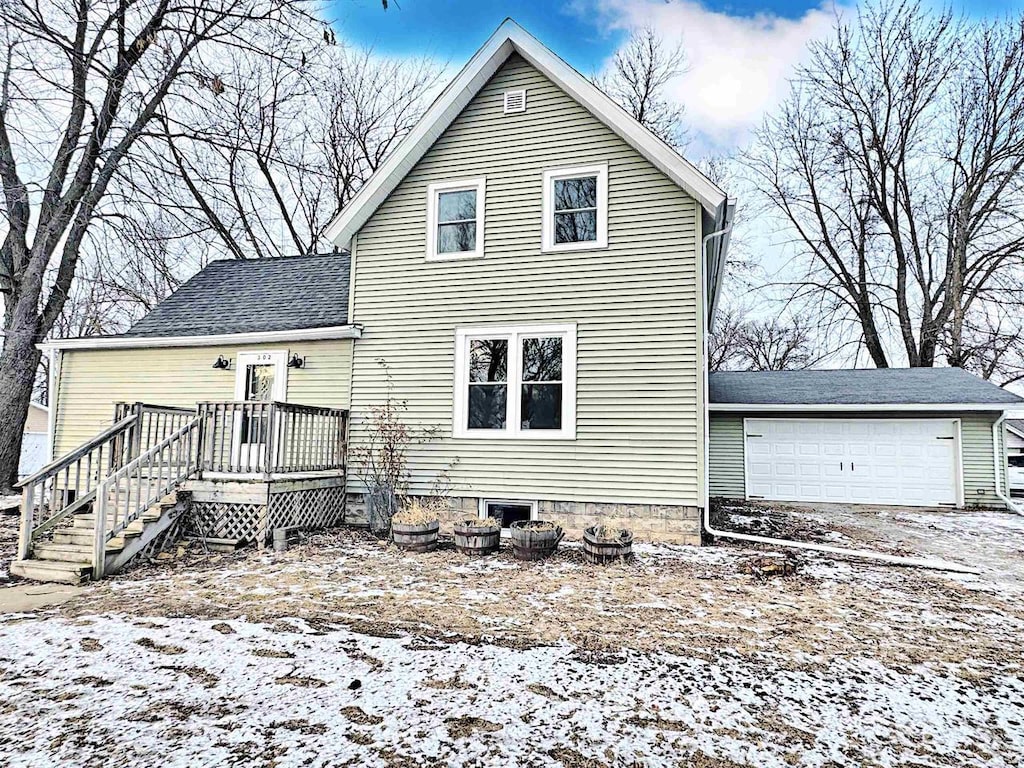 snow covered house featuring a garage and a wooden deck