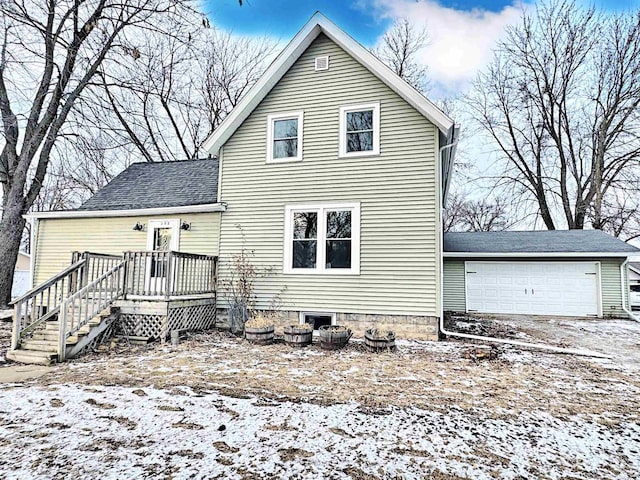 snow covered house featuring a garage and a wooden deck