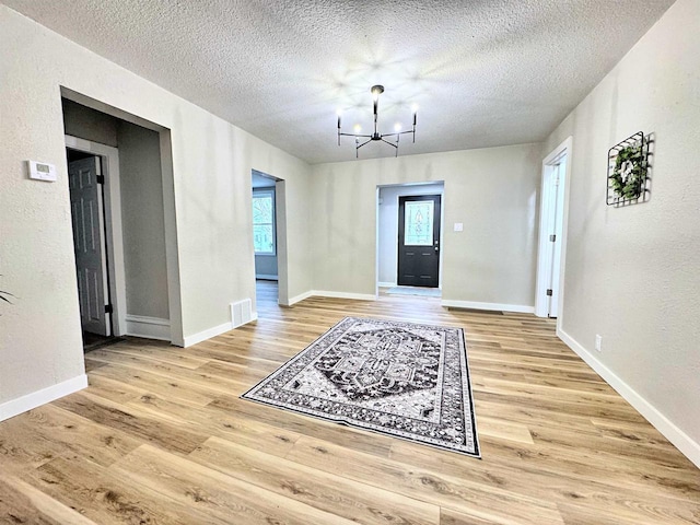 entrance foyer featuring wood-type flooring, a textured ceiling, and a notable chandelier