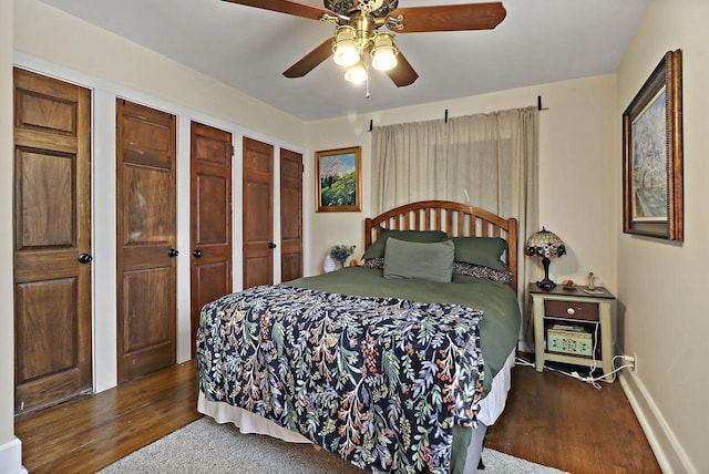 bedroom featuring hardwood / wood-style floors, multiple closets, and ceiling fan