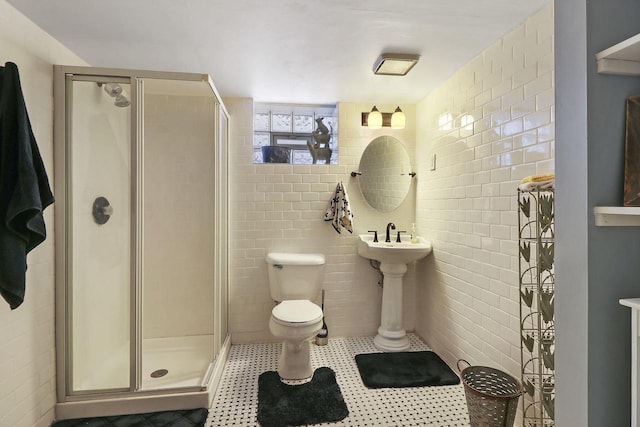 bathroom with tile walls, a shower with shower door, and toilet