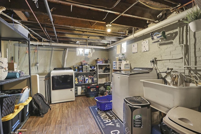 basement featuring sink, washing machine and dryer, and hardwood / wood-style flooring