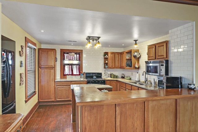 kitchen featuring sink, tasteful backsplash, kitchen peninsula, dark hardwood / wood-style flooring, and black appliances