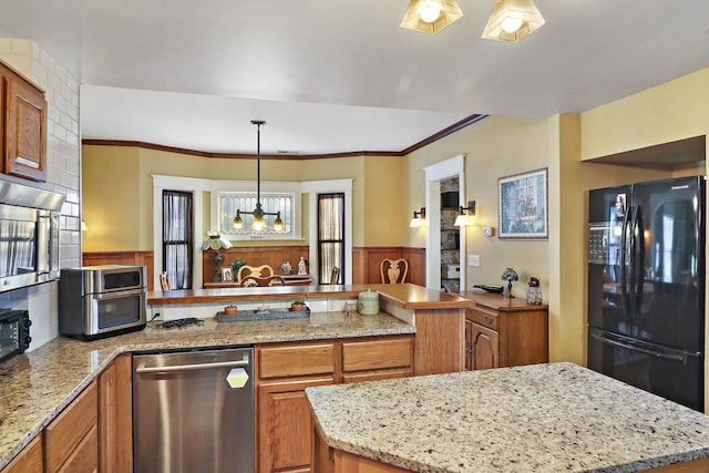 kitchen featuring light stone counters, dishwasher, pendant lighting, black refrigerator, and a kitchen island