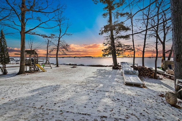 yard at dusk featuring a playground and a water view