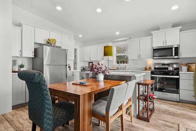 kitchen with stainless steel appliances, crown molding, white cabinets, light hardwood / wood-style flooring, and sink