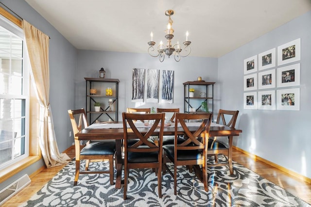 dining space with light hardwood / wood-style floors and a chandelier