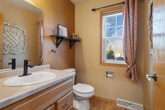 bathroom with toilet, vanity, and hardwood / wood-style flooring