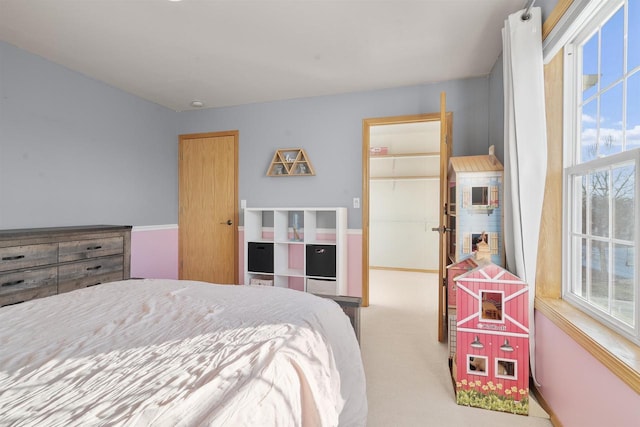 carpeted bedroom with a closet and a spacious closet