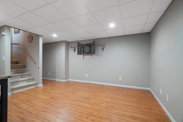 basement featuring light wood-type flooring and a drop ceiling