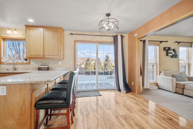 kitchen with light hardwood / wood-style flooring, decorative light fixtures, a notable chandelier, light brown cabinets, and sink