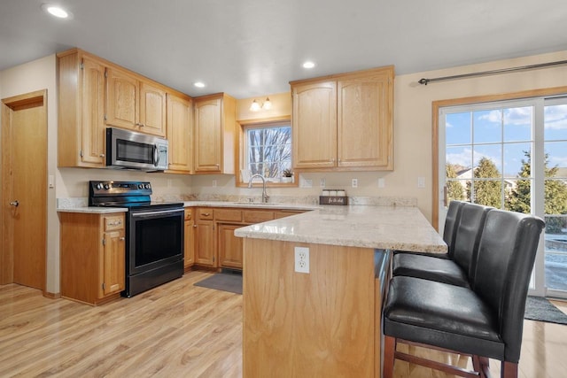 kitchen with kitchen peninsula, light brown cabinetry, a kitchen bar, light wood-type flooring, and electric range oven