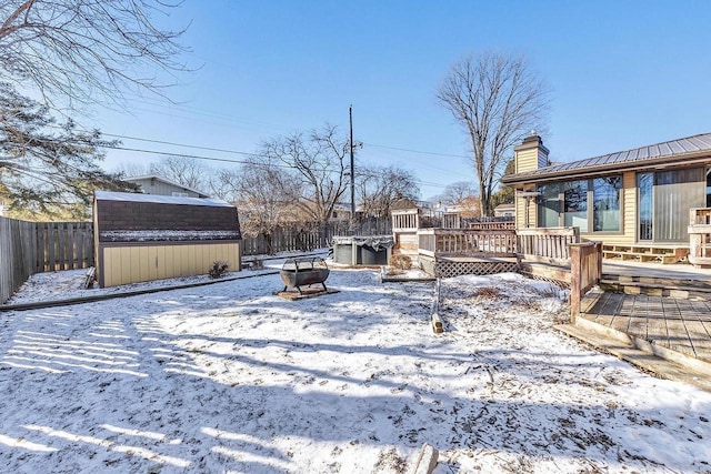 yard layered in snow featuring a wooden deck and an outdoor fire pit