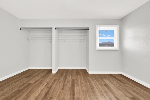 unfurnished bedroom with two closets and hardwood / wood-style floors