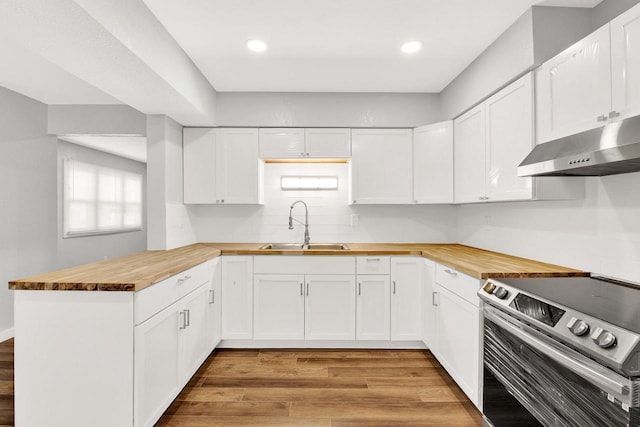 kitchen with butcher block counters, sink, white cabinets, light wood-type flooring, and electric range