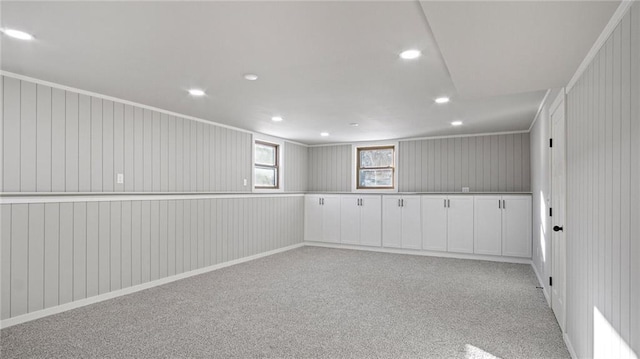 empty room featuring light colored carpet, ornamental molding, and wooden walls