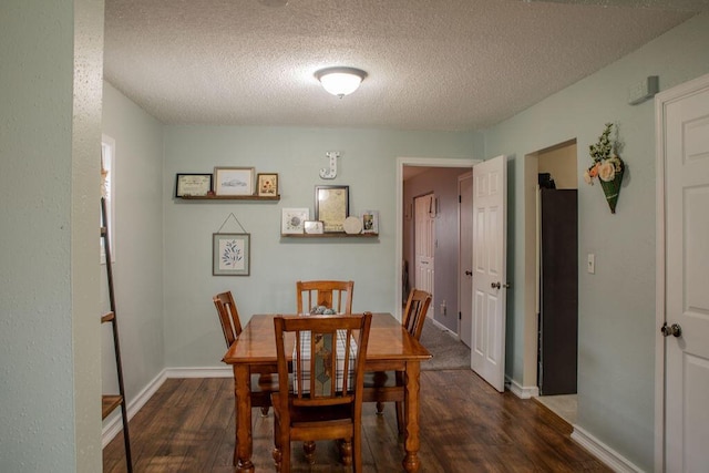 dining room featuring dark wood-type flooring and a textured ceiling