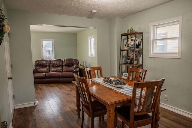 dining room with a textured ceiling and dark hardwood / wood-style flooring