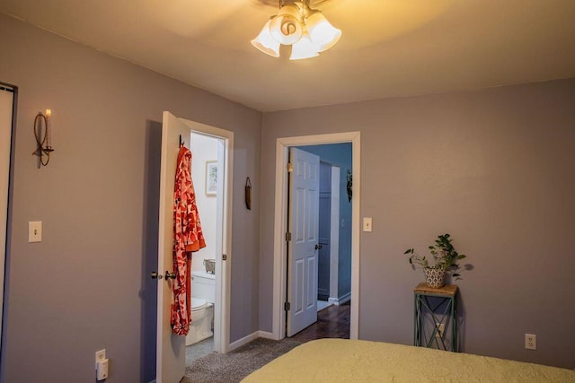 unfurnished bedroom featuring ensuite bath, ceiling fan, and dark carpet