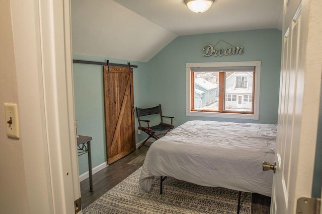 bedroom featuring lofted ceiling, dark hardwood / wood-style flooring, and a barn door