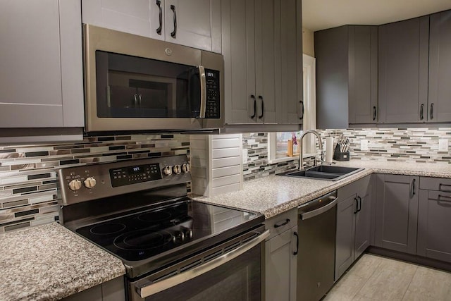 kitchen featuring sink, light stone countertops, backsplash, and appliances with stainless steel finishes