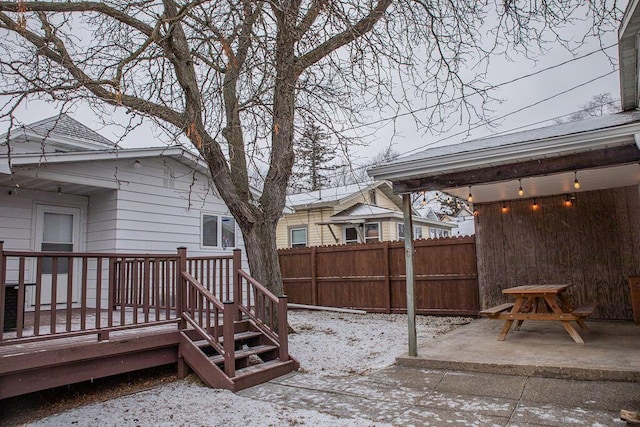 yard layered in snow featuring a patio and a wooden deck