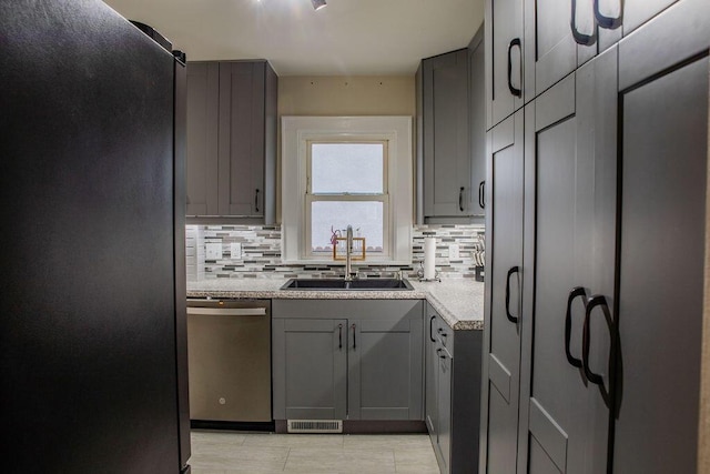 kitchen featuring dishwasher, black refrigerator, backsplash, gray cabinetry, and sink