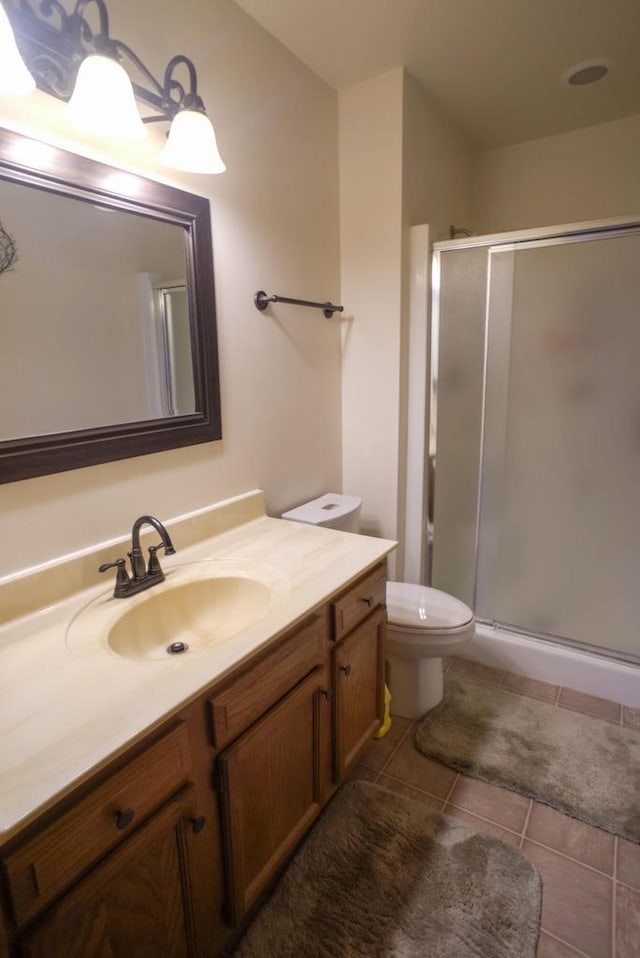 bathroom with a shower with door, tile patterned floors, vanity, and toilet