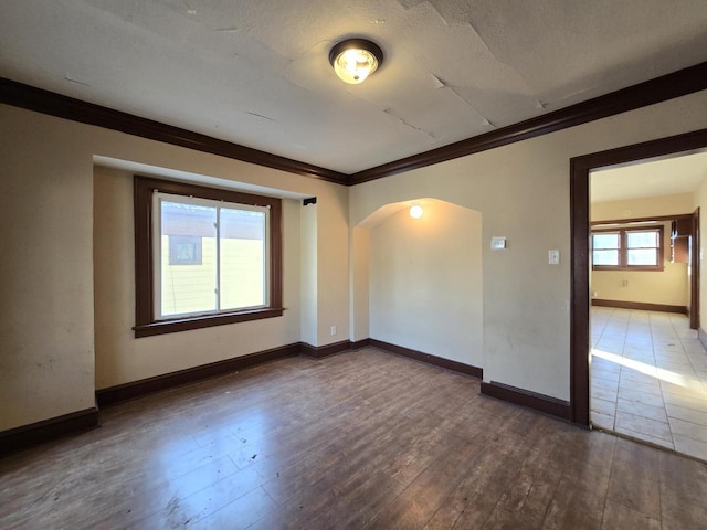 empty room featuring a textured ceiling, ornamental molding, and dark hardwood / wood-style floors