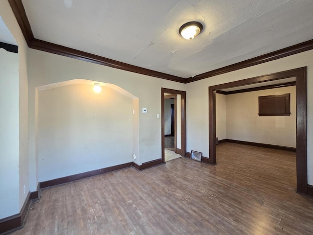 spare room featuring crown molding and dark wood-type flooring