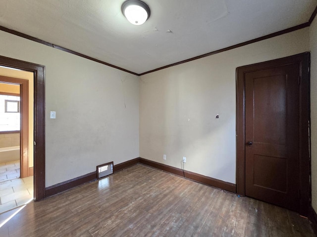 empty room with crown molding and wood-type flooring