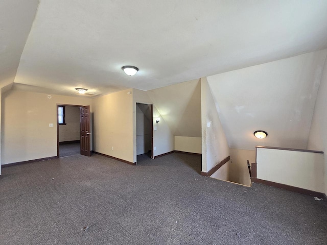 unfurnished room with vaulted ceiling and dark carpet