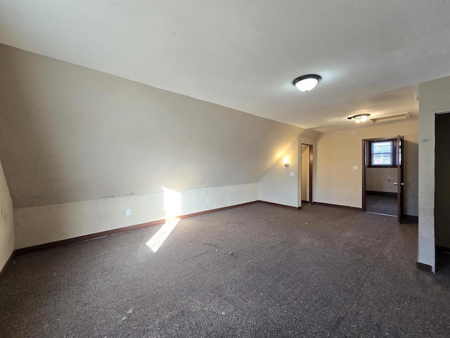 spare room with vaulted ceiling and dark colored carpet