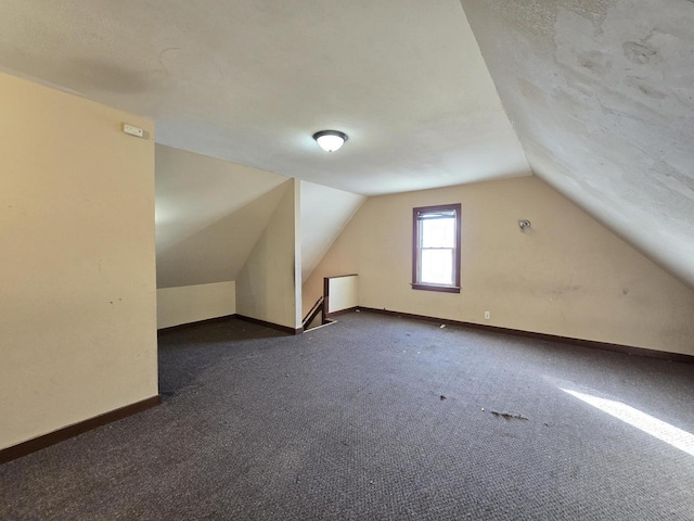 additional living space featuring lofted ceiling and dark carpet