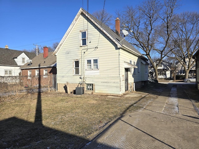 back of property with central air condition unit and a yard