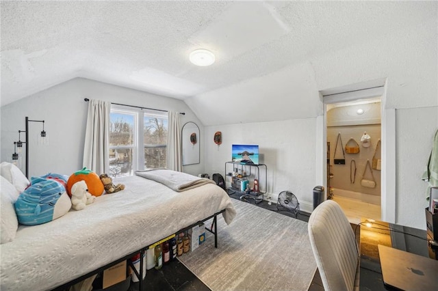 bedroom featuring ensuite bathroom, vaulted ceiling, and a textured ceiling