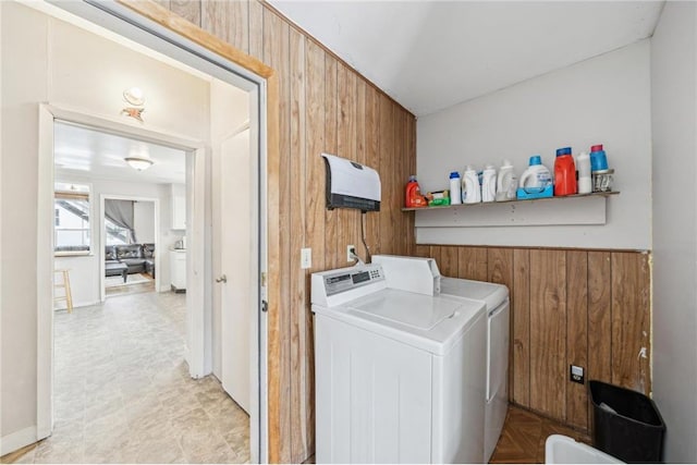 laundry room with wood walls and washing machine and clothes dryer