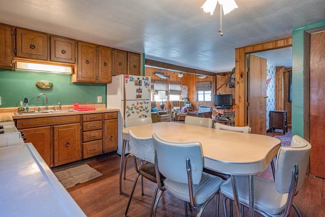 kitchen with white refrigerator, wooden walls, dark hardwood / wood-style flooring, and sink