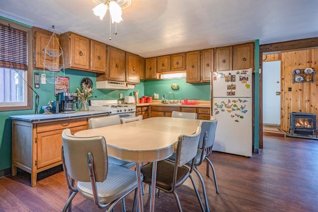 kitchen with sink, dark hardwood / wood-style flooring, white appliances, and a wood stove